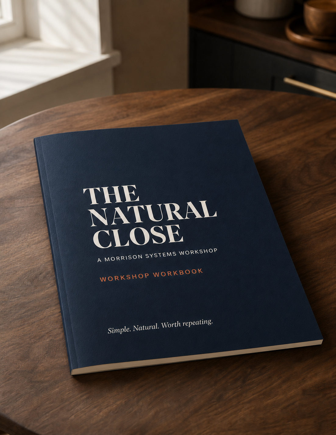 A slim Natural Close workshop workbook on a warm wood table